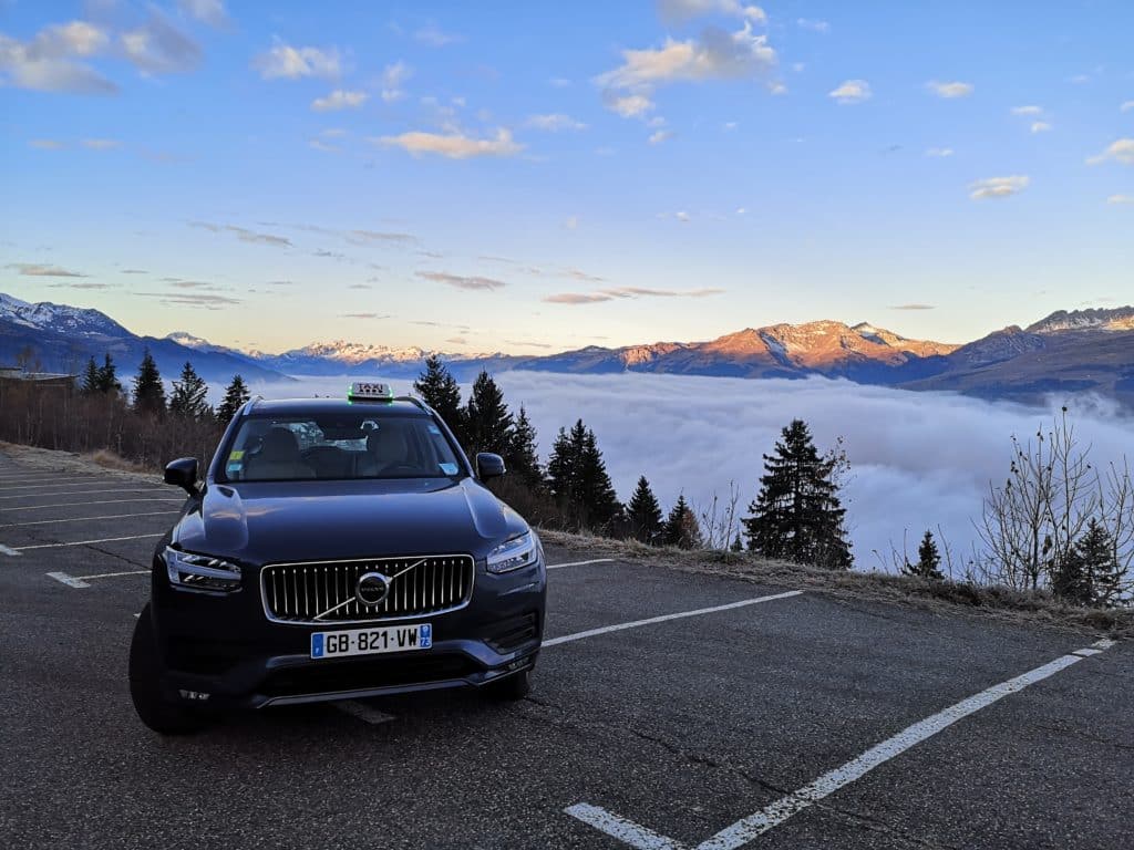 Le véhicule d'Alaska Taxi devant une mer de nuage, photo prise depuis la station de ski Les Arcs